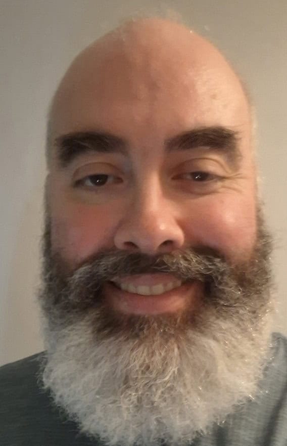 Close-up of a smiling man with a beard, representing a healer at Light Axis Healing in Sydney.
